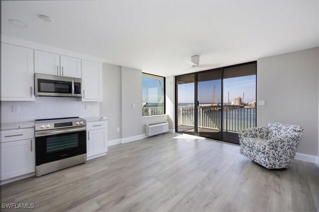 kitchen with white cabinetry, light wood-type flooring, a water view, and appliances with stainless steel finishes