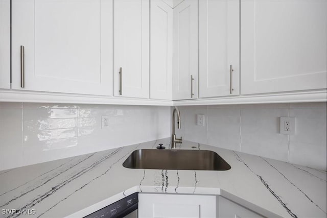 kitchen featuring sink, light stone countertops, and white cabinets