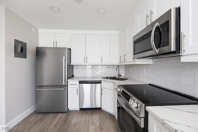 kitchen with appliances with stainless steel finishes, light stone countertops, sink, and white cabinets