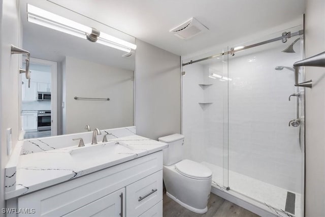 bathroom featuring walk in shower, vanity, toilet, and hardwood / wood-style floors