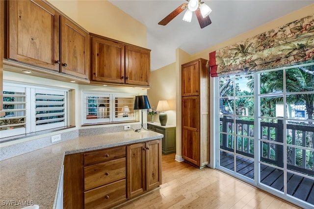 kitchen with light stone counters, ceiling fan, and light hardwood / wood-style flooring