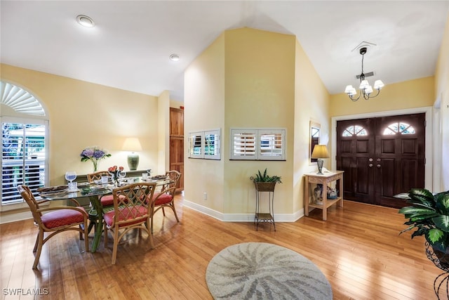 foyer entrance with a notable chandelier, light hardwood / wood-style flooring, and high vaulted ceiling