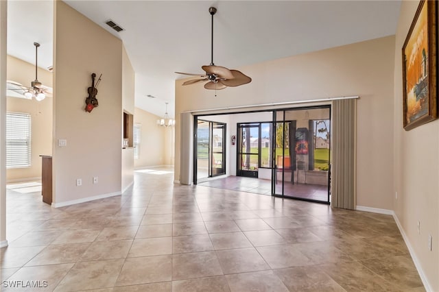 spare room with a wealth of natural light, ceiling fan with notable chandelier, and light tile patterned flooring