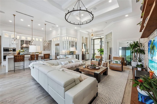 living room featuring crown molding, a chandelier, light hardwood / wood-style flooring, a raised ceiling, and a high ceiling