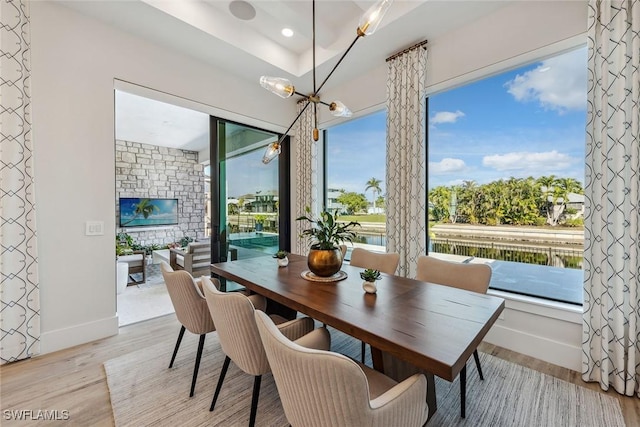 dining room featuring a water view, a chandelier, and light wood-type flooring