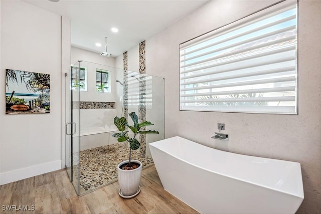 bathroom with hardwood / wood-style flooring and shower with separate bathtub