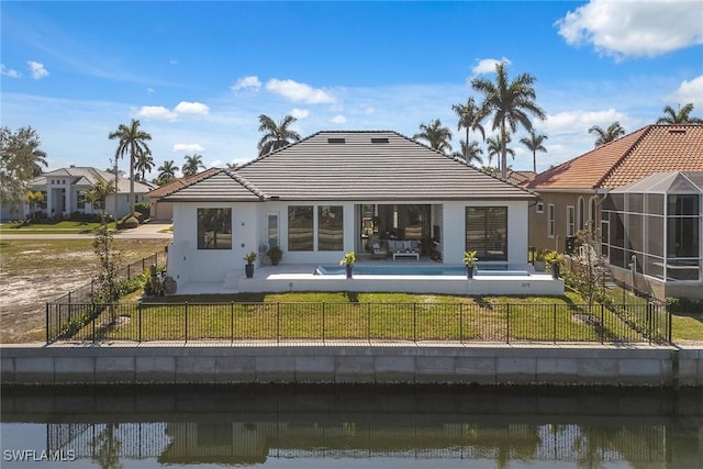 back of property featuring a yard, glass enclosure, and a water view