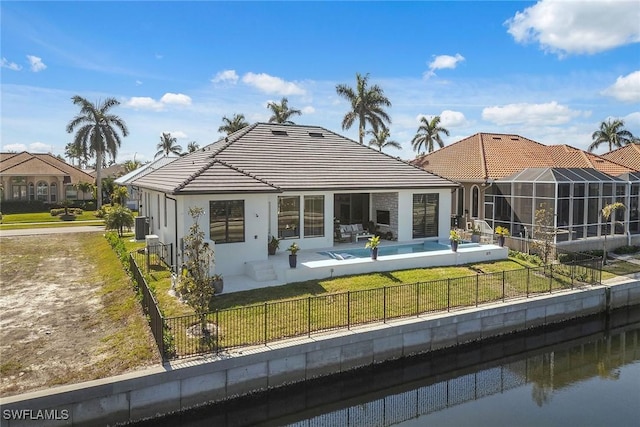 rear view of house featuring a lawn, a lanai, a fenced in pool, a water view, and a patio area