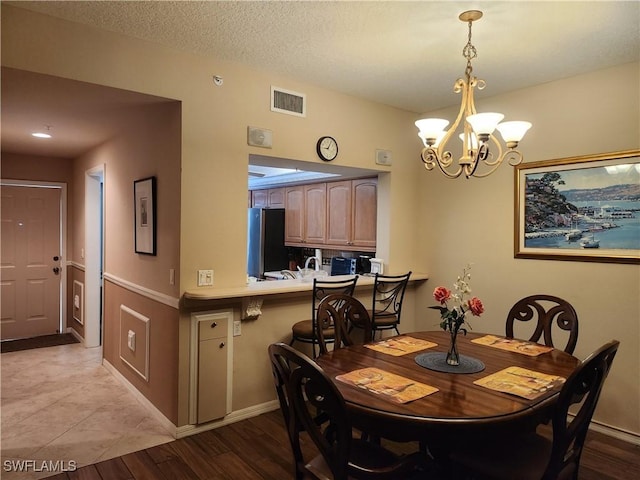 dining room with a chandelier, a textured ceiling, and light hardwood / wood-style flooring