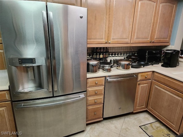 kitchen with light tile patterned flooring, appliances with stainless steel finishes, and backsplash