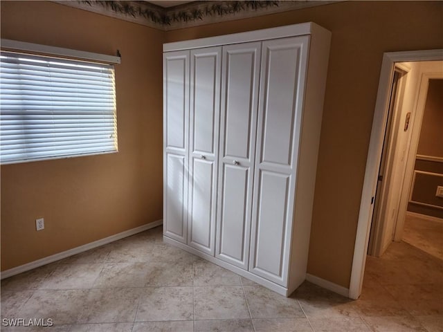 unfurnished bedroom with light tile patterned floors and a closet