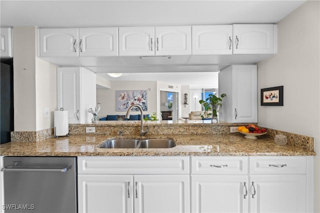 kitchen with light stone counters, sink, stainless steel dishwasher, and white cabinets