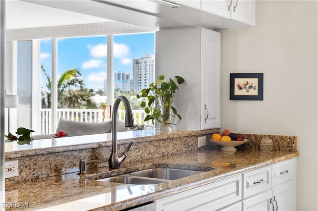 kitchen featuring light stone countertops, sink, and white cabinets