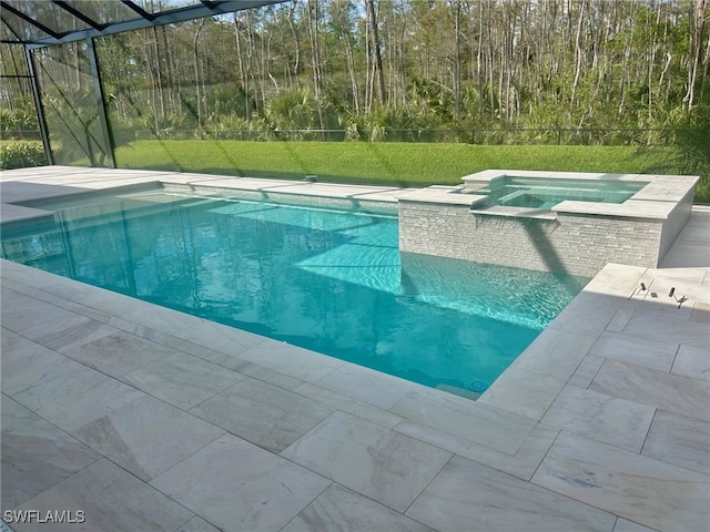 view of pool featuring glass enclosure, a pool with connected hot tub, a patio area, and a lawn