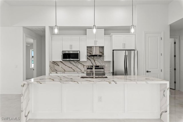 kitchen featuring wall chimney range hood, hanging light fixtures, appliances with stainless steel finishes, and white cabinetry