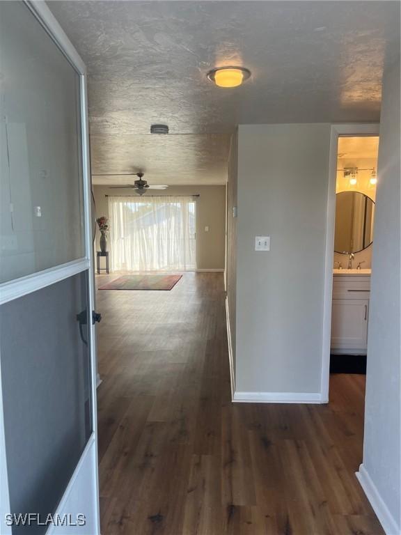 hallway with dark hardwood / wood-style flooring, sink, and a textured ceiling