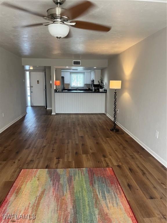 unfurnished living room with dark wood-type flooring and ceiling fan