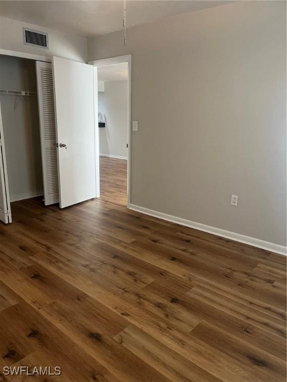 unfurnished bedroom featuring dark hardwood / wood-style flooring and a closet