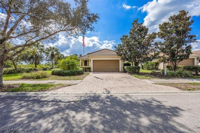 view of front facade featuring decorative driveway, a tiled roof, an attached garage, and stucco siding