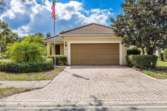 view of front of home with a garage, a tiled roof, decorative driveway, and stucco siding