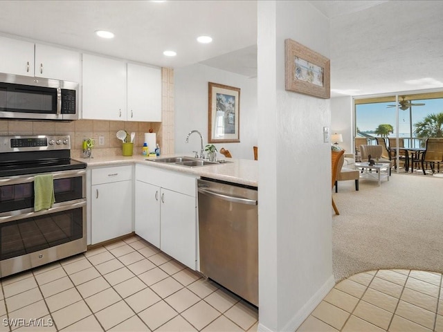 kitchen featuring sink, light carpet, appliances with stainless steel finishes, white cabinets, and backsplash