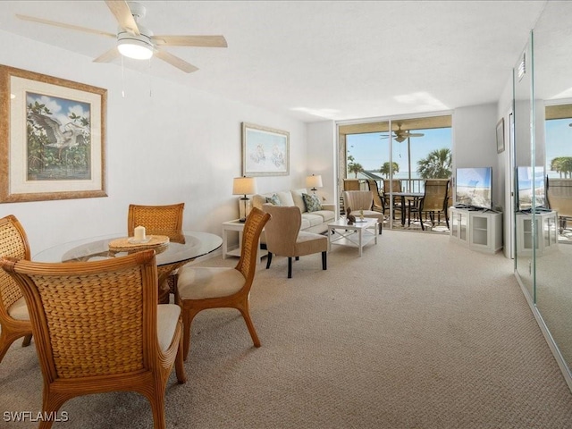 sitting room featuring expansive windows, ceiling fan, and carpet flooring