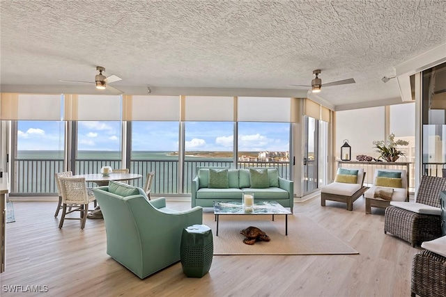 sunroom featuring a water view and ceiling fan