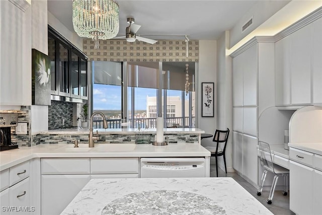 kitchen with white dishwasher, sink, tasteful backsplash, and white cabinets