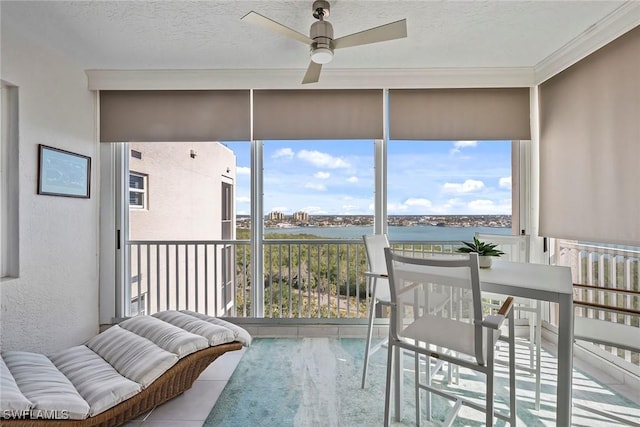 sunroom / solarium featuring ceiling fan and a water view