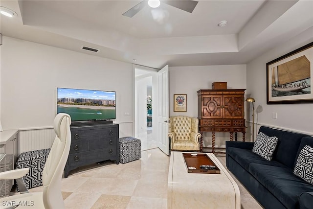 living room featuring a raised ceiling and ceiling fan