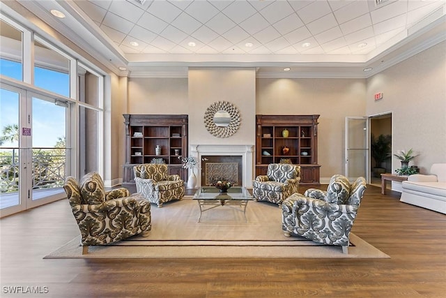 living room with french doors, wood-type flooring, ornamental molding, a tray ceiling, and a towering ceiling