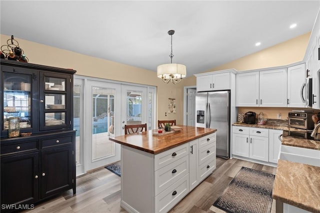 kitchen with stainless steel appliances, a kitchen island, hanging light fixtures, and white cabinetry