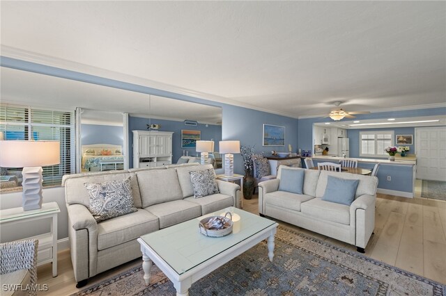 living room featuring ornamental molding, ceiling fan, and light wood-type flooring