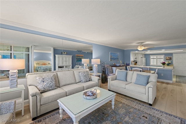 living room featuring ornamental molding, light wood finished floors, and a ceiling fan