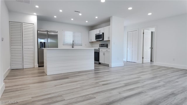 kitchen featuring light hardwood / wood-style floors, a center island, white cabinets, and appliances with stainless steel finishes