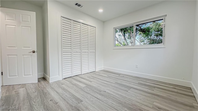 unfurnished bedroom with light wood-type flooring and a closet