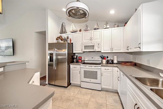 kitchen featuring white appliances, light tile patterned floors, sink, and white cabinets