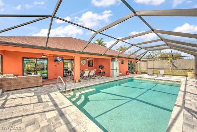 view of swimming pool with ceiling fan, outdoor lounge area, a patio area, and glass enclosure