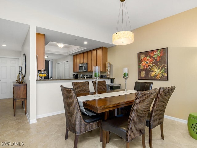 dining room featuring a tray ceiling and light tile patterned flooring