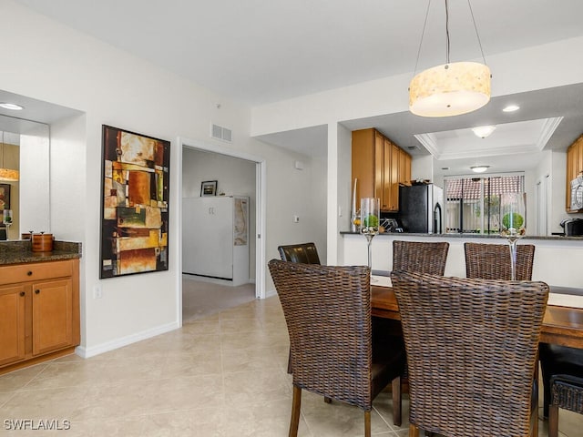 dining space with light tile patterned flooring and a tray ceiling