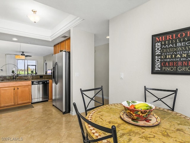 dining space with sink, light tile patterned floors, and a tray ceiling