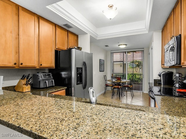 kitchen featuring light tile patterned flooring, a tray ceiling, light stone counters, kitchen peninsula, and stainless steel appliances