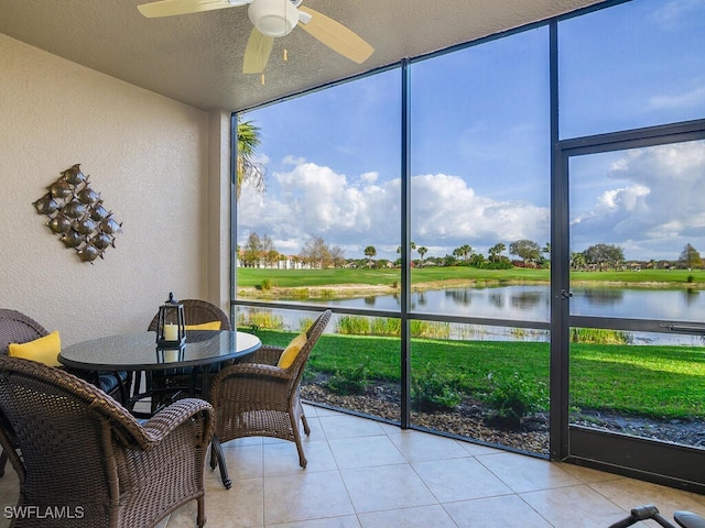 sunroom / solarium with ceiling fan and a water view