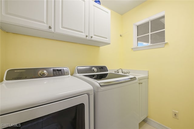 laundry room featuring washer and clothes dryer and cabinets