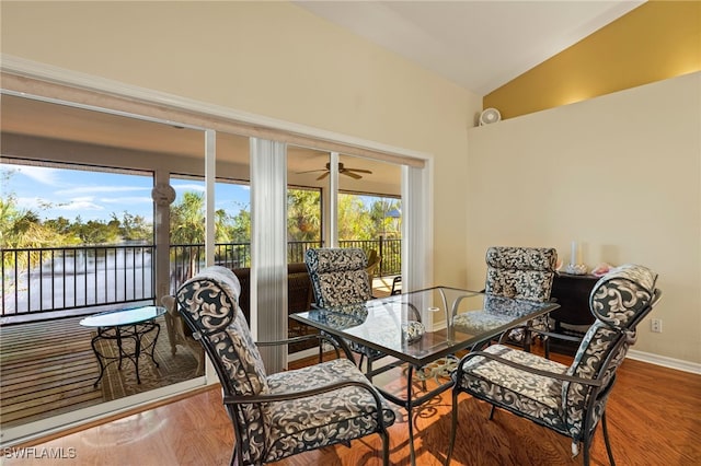 dining area featuring hardwood / wood-style flooring, a water view, and lofted ceiling