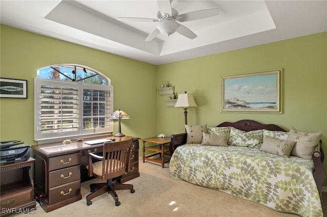 bedroom featuring light carpet, ceiling fan, and a tray ceiling