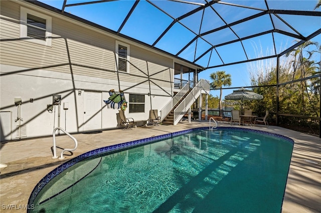 view of swimming pool featuring glass enclosure and a patio area