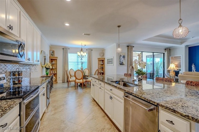 kitchen featuring pendant lighting, stainless steel appliances, light stone countertops, ornamental molding, and white cabinets