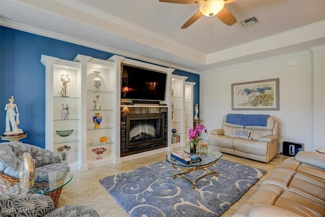 living room with tile patterned flooring, ornamental molding, ceiling fan, and a tray ceiling