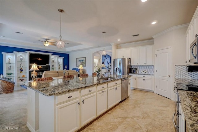 kitchen with appliances with stainless steel finishes, stone countertops, decorative light fixtures, an island with sink, and sink